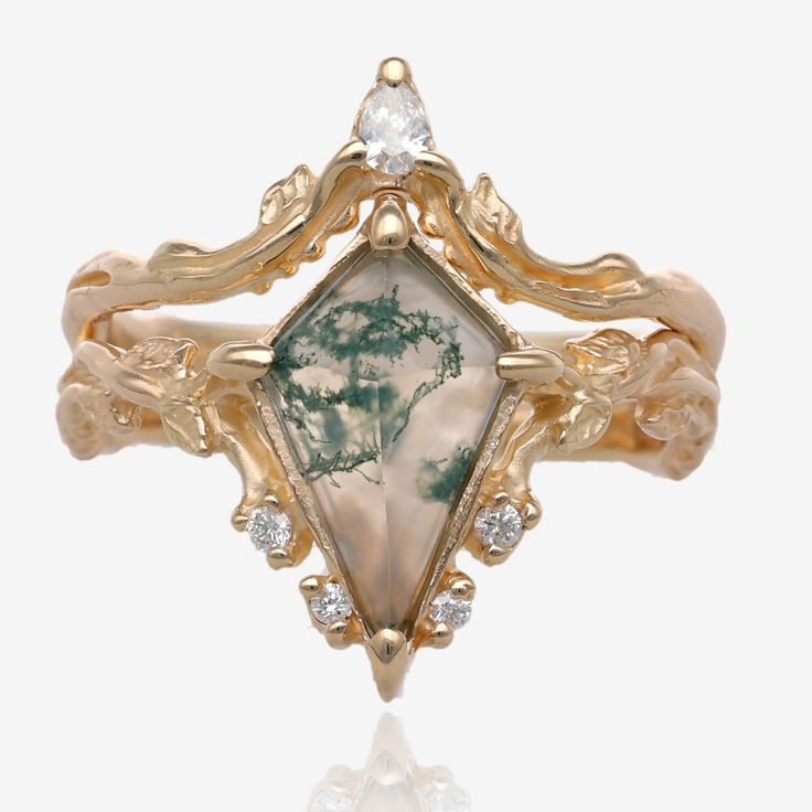 A two piece yellow gold wedding ring set wider on top tapering on the bottom. White background. Gemstone inset is translucent white with threads of green curling through the stone. It is kite shaped with the narrower point on top, and in a bezel and prong set. The wedding ring has a teardrop shaped diamond, and the engagement ring has tiny diamonds in leaves, accenting the agate. Faerie Crown, Green Wedding Rings, Nature Inspired Wedding, Enchanted Wedding, Traditional Engagement Rings, Agate Engagement Ring, Diamond Gift, Yellow Gold Engagement, Silver Jewelry Fashion