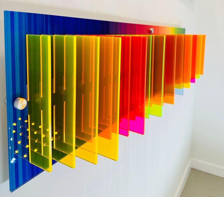 a rainbow colored piece of art hanging on the wall