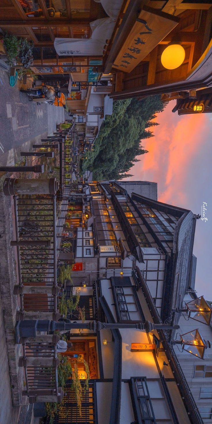 an aerial view of a city street at dusk, with buildings and trees in the foreground