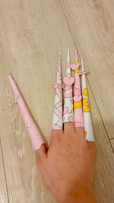 a hand holding three pink and white toothbrushes on top of a wooden floor