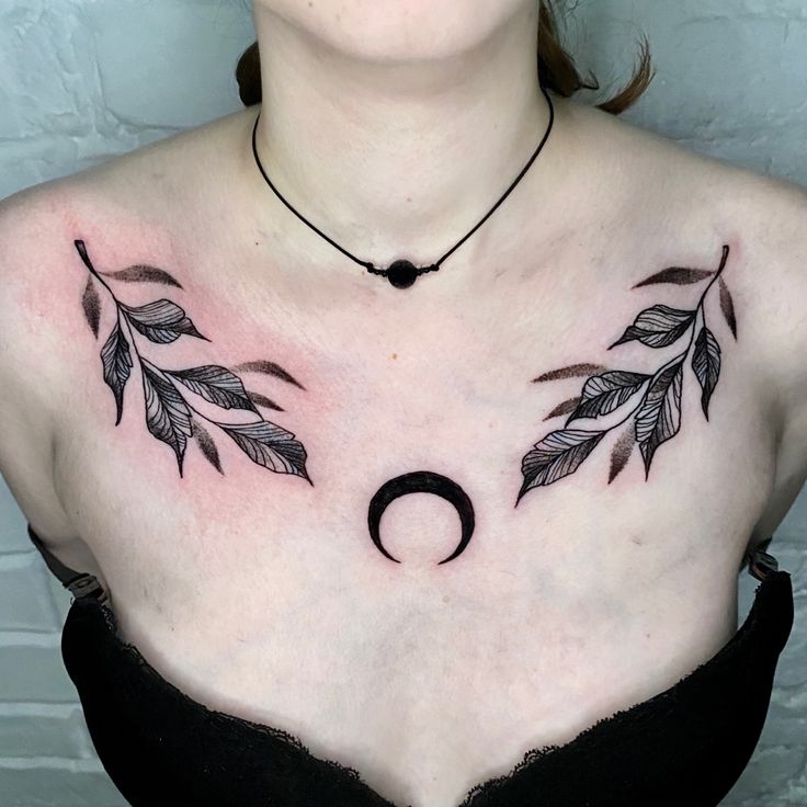 a woman with tattoos on her chest has a crescent and leaves tattoo on her chest