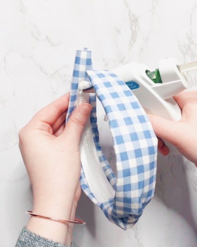 a woman is sewing a blue and white checkered tie