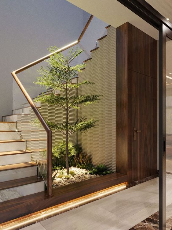 a small tree in the middle of a room with stairs leading up to an entrance