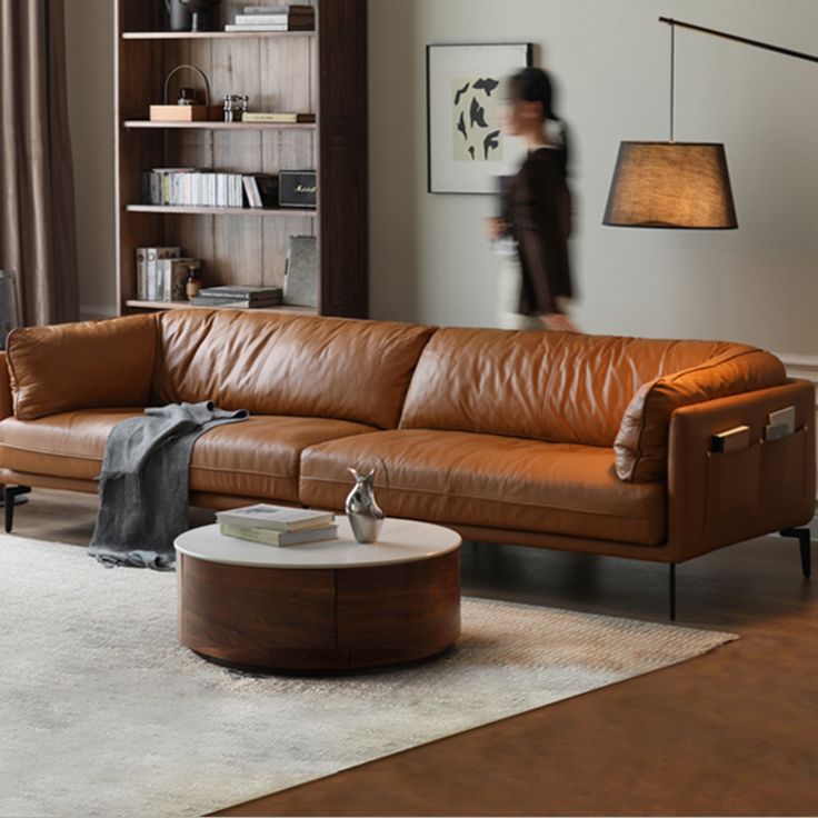 a living room with a brown leather couch and coffee table in front of a book shelf