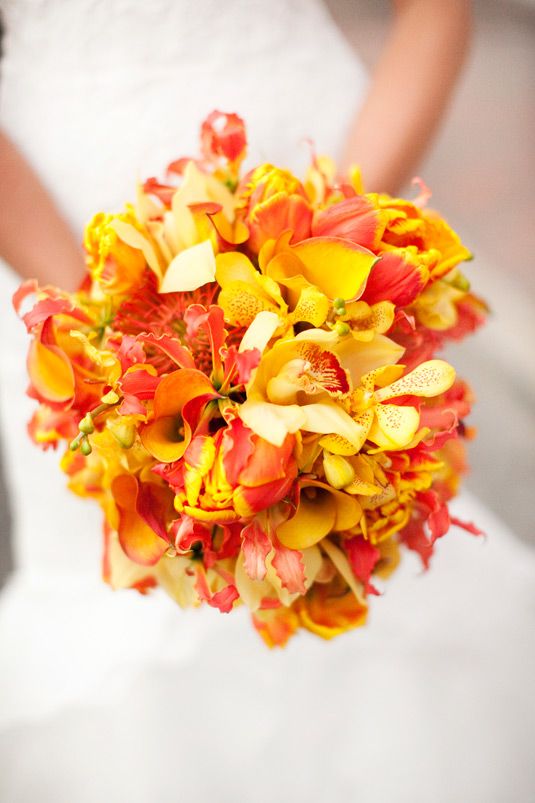 a bride holding a bouquet of orange and yellow flowers