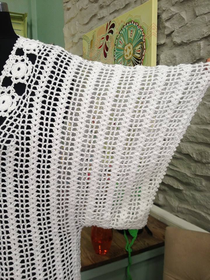 a white crocheted shawl hanging from a hook