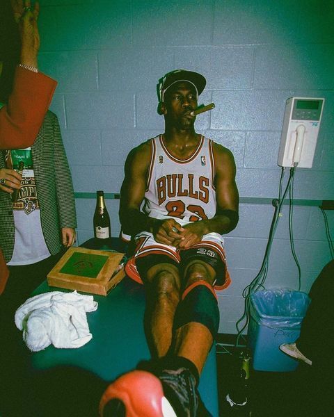 a man sitting on top of a bed next to a basketball ball and a bottle