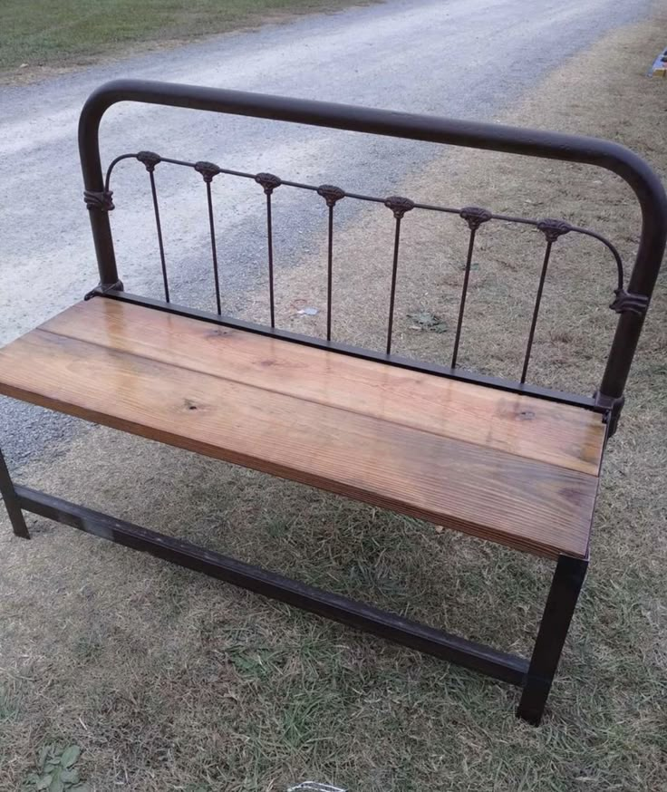 a wooden bench sitting on top of a grass covered field next to a dirt road