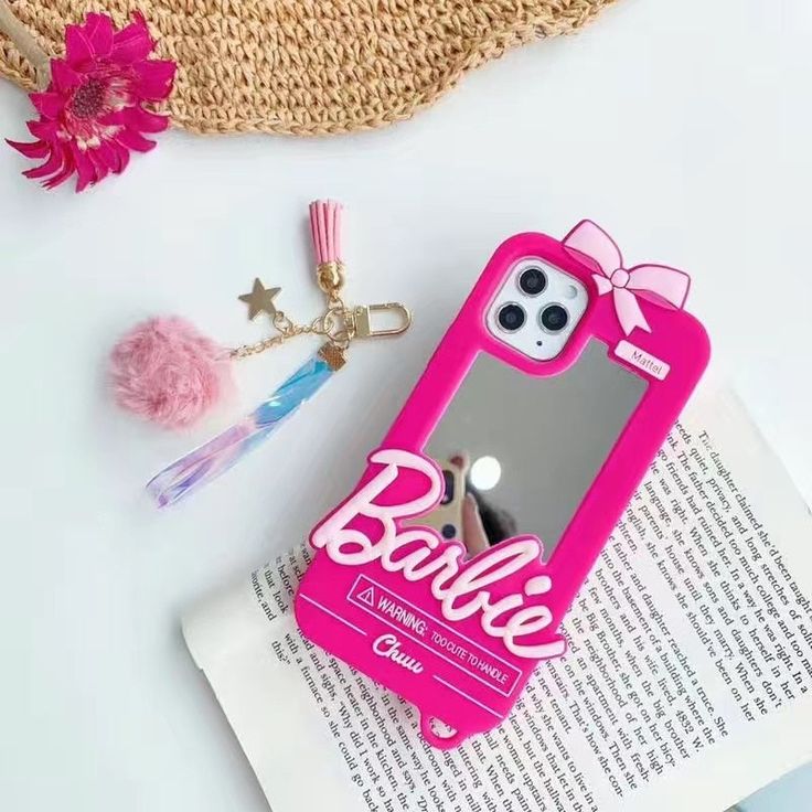 a pink phone case sitting on top of an open book next to a keychain