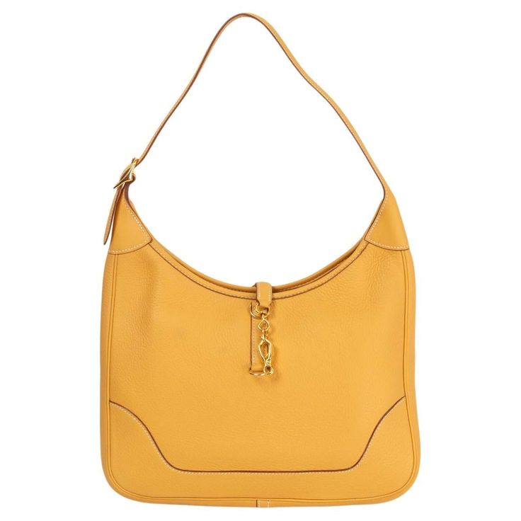 100% authentic Hermès Trim 31 hobo in Curry yellow soft Taurillon Clemence leather featuring gold-tone hardware. Designed with adjustable shoulder handle, clasp opening with top zipper closure and gusseted sides. Unlined interior with a one slip compartment and a zipper pockets against the back. Has been carried and shows some barely visible darker spots at front and back and a moth ball scent. Overall in excellent condition. Comes with dust bag. Measurements Height 21cm (8.2in) Width 31cm (12.1 Hermes Trim Bag, Curry Yellow, Hermes Orange, Yellow Soft, Bag Measurements, Hermes Bags, Hermes Bag, Gold Leather, Hobo Bag