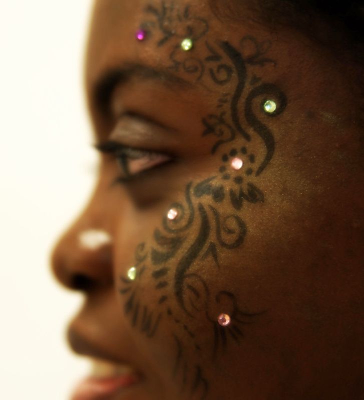 a woman's face with tattoos and piercings on her forehead, looking at the camera