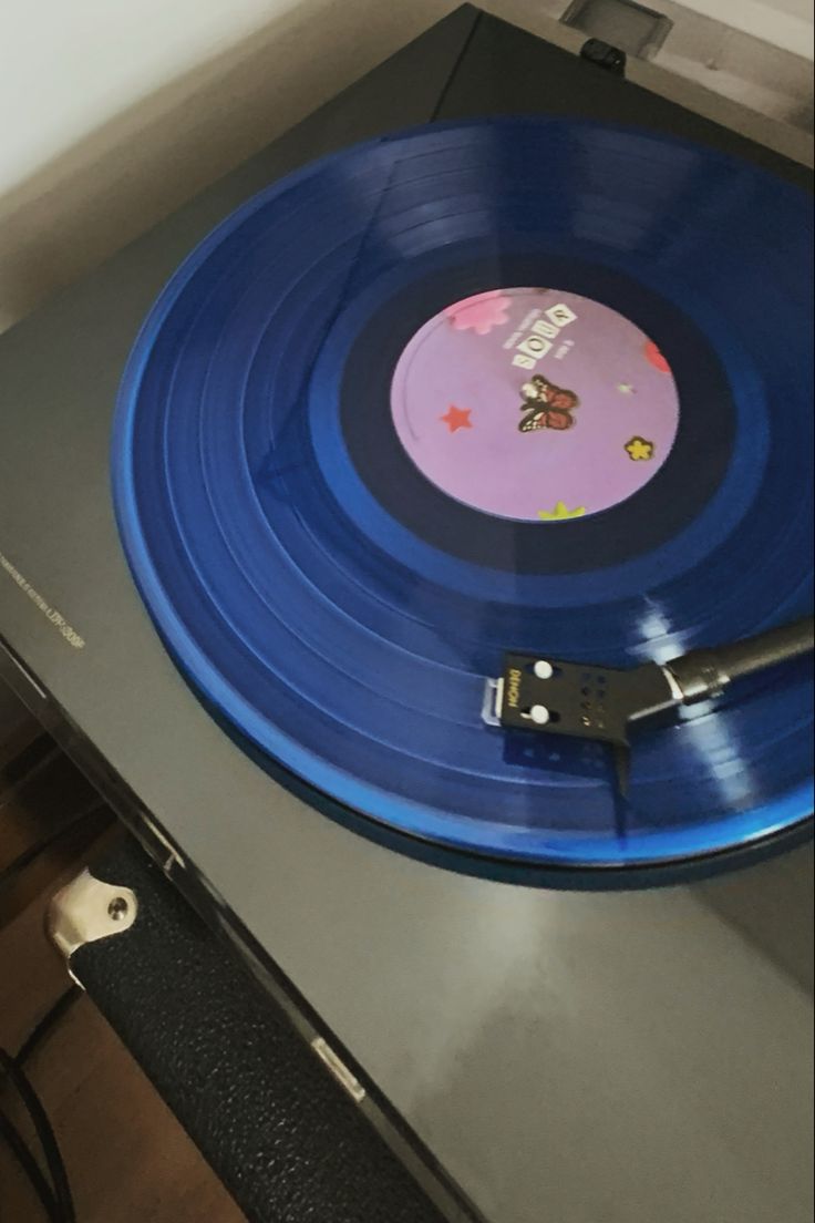 a blue record player sitting on top of a metal table next to a white wall