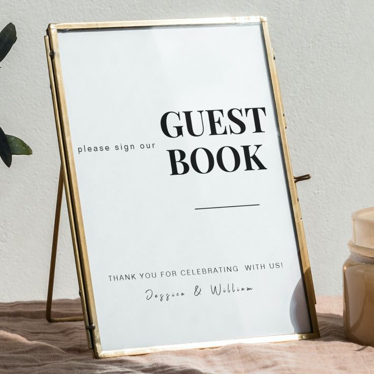 a guest book sign sitting on top of a bed next to a jar of honey