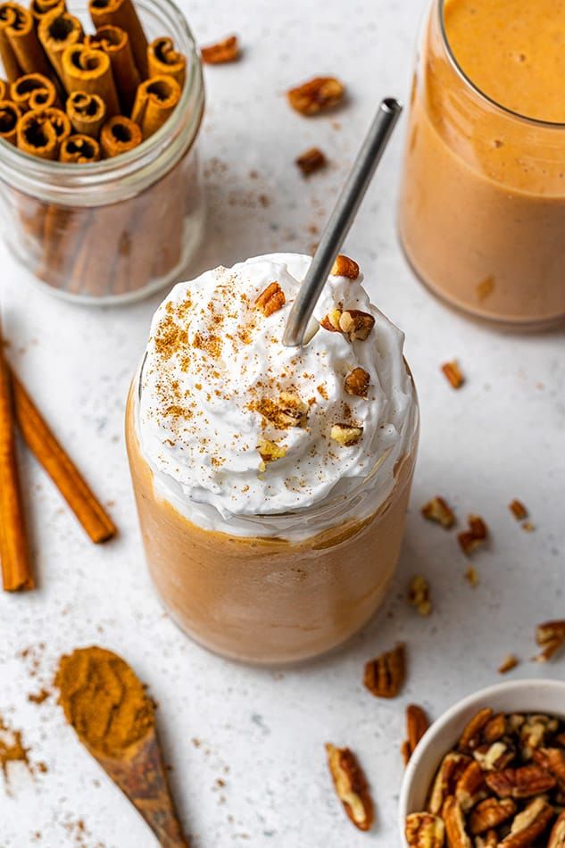 two cups filled with hot chocolate and topped with whipped cream, cinnamon sticks and pretzels