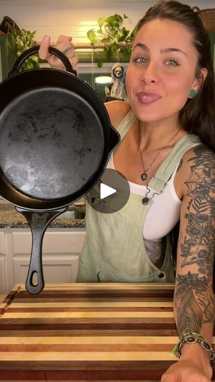 a woman holding up a frying pan on top of a wooden table