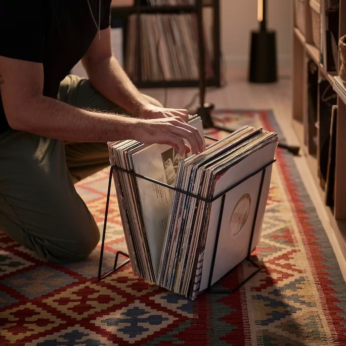 a man kneeling down on the floor next to a stack of records