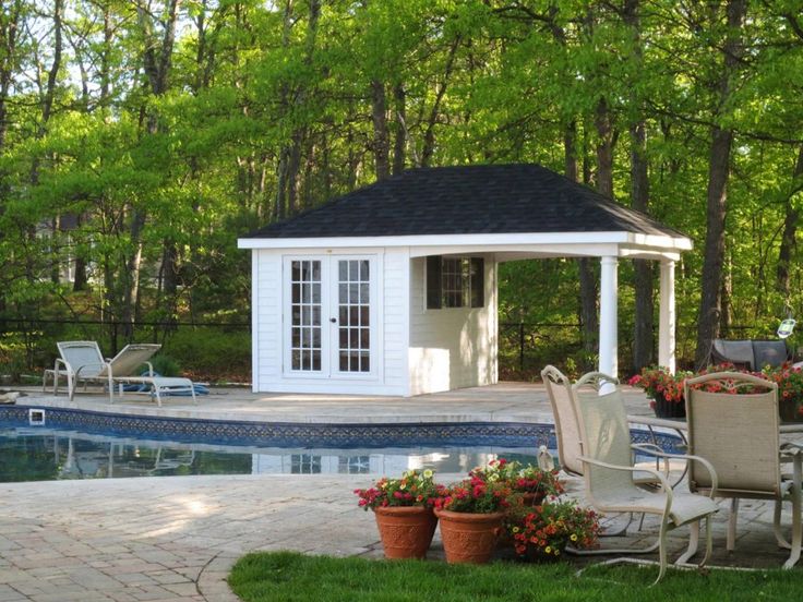 a gazebo next to a swimming pool surrounded by greenery and flowers with chairs around it