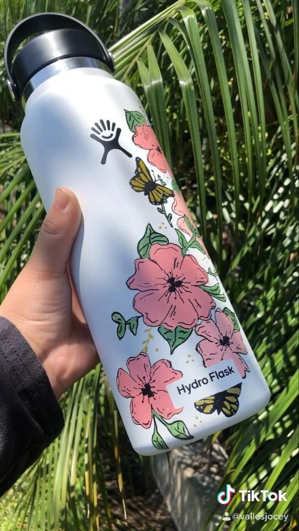 someone is holding a water bottle with flowers on it