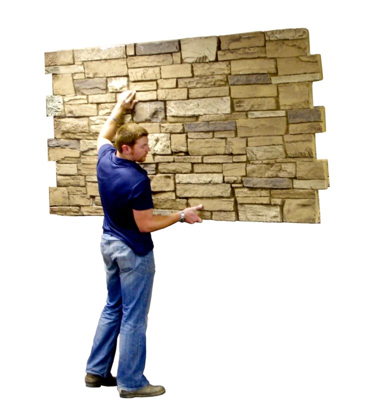 a man standing in front of a wall made out of blocks of wood and bricks