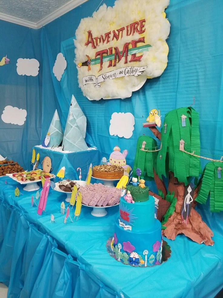 a table topped with lots of cakes and desserts next to a sign that says adventure time