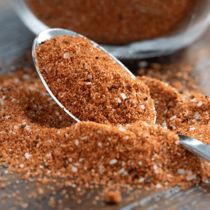 a spoon filled with ground spices on top of a wooden table