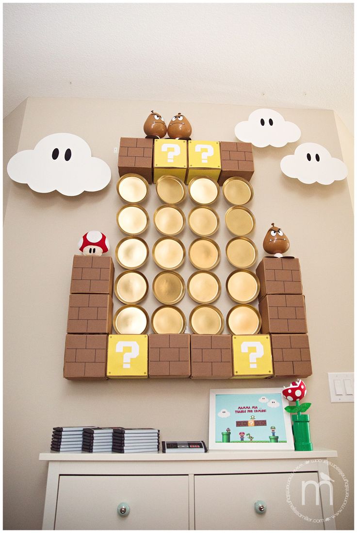 a nintendo themed wall hanging above a dresser in a room with white walls and clouds