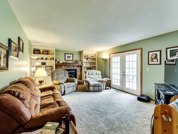 a living room filled with furniture and a flat screen tv mounted on a wall next to a doorway