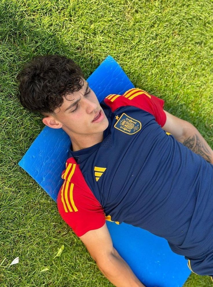 a young man laying on top of a blue mat in the grass with a frisbee