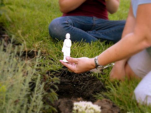 two people kneeling down in the grass holding small bottles