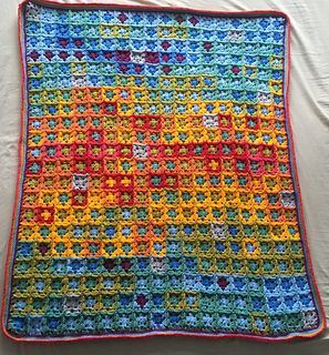 a multicolored crocheted blanket is laying on a bed