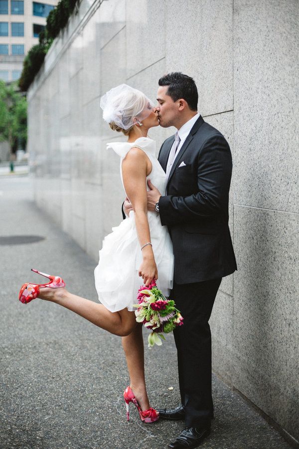 a bride and groom kissing in front of a wall with their feet on the ground