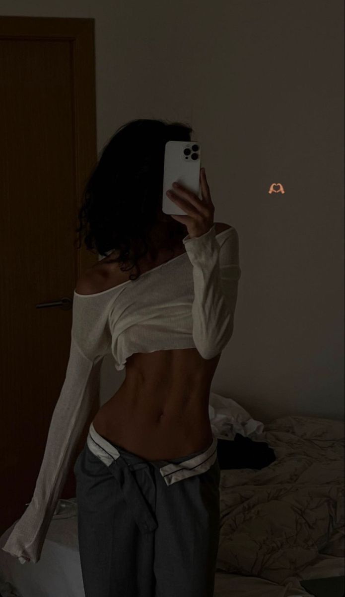 a woman taking a selfie with her cell phone in the dark while wearing sweatpants