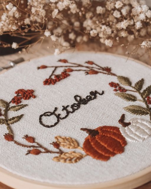 a close up of a embroidery on a wooden hoop with flowers and leaves around it