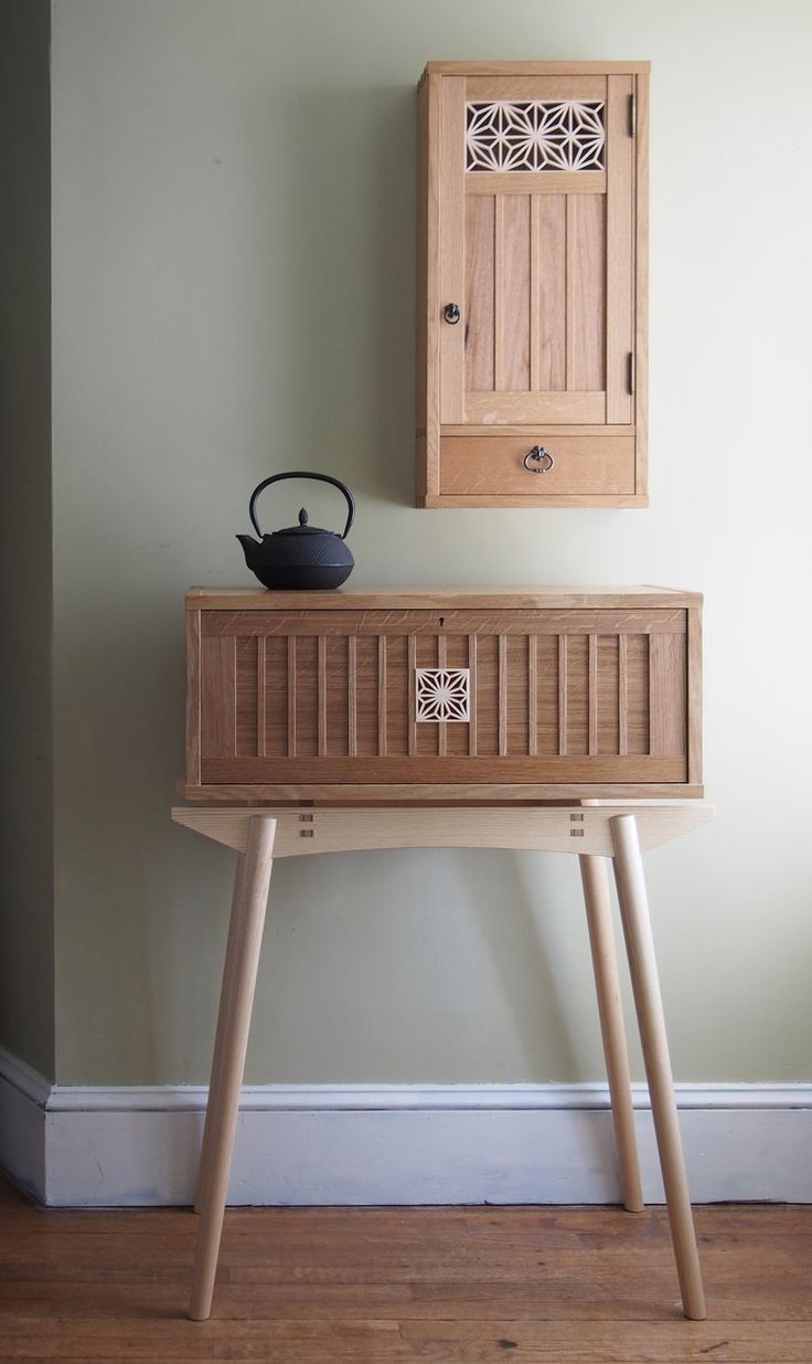 a wooden cabinet sitting on top of a hard wood floor next to a white wall