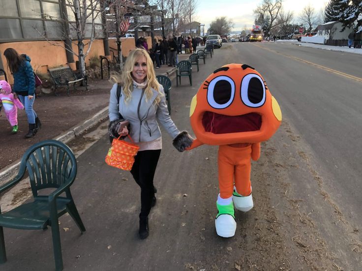 a woman is walking down the street with an orange stuffed animal in her hand and smiling at the camera