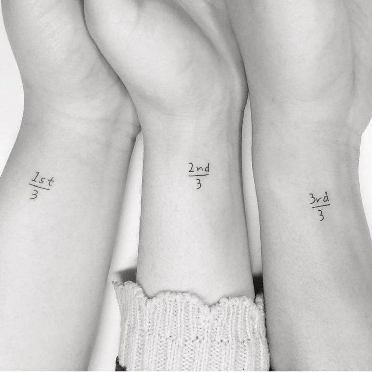 three people with matching tattoos on their arms holding each other's hands in the air