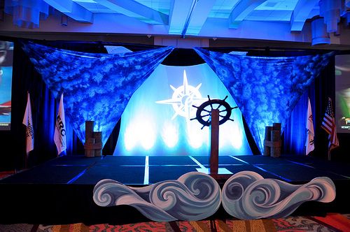 the stage is set up for an event with blue lighting and decorative waves on it