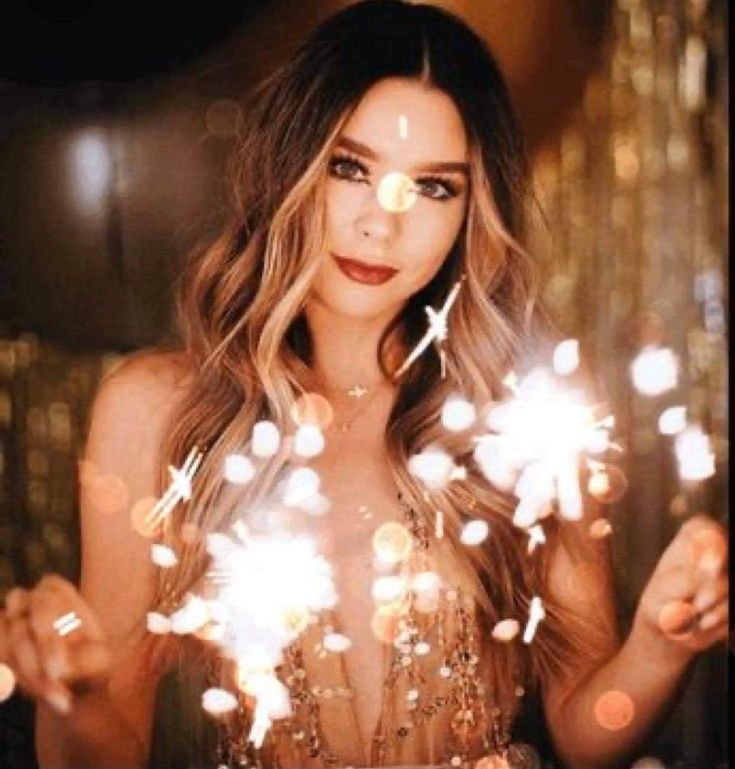 a woman holding sparklers in front of her face