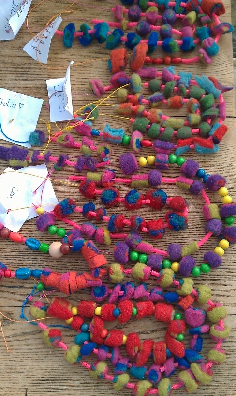 colorful beads and paper on a wooden table with string attached to the bead ends