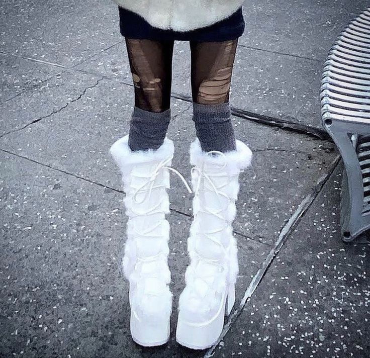 a woman in white boots standing next to a bench