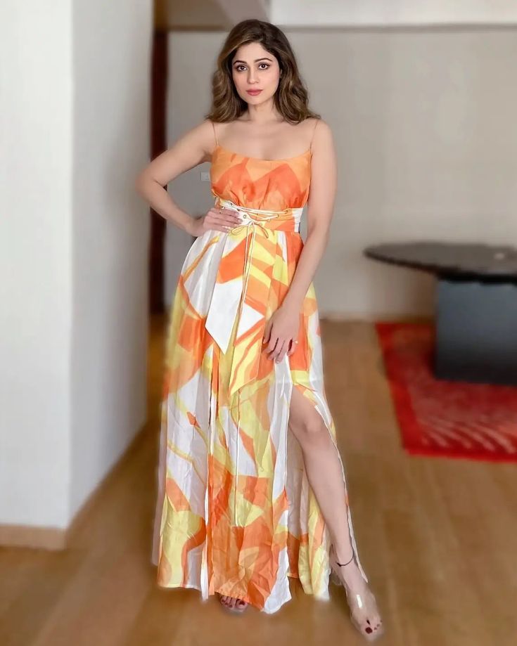 a woman in an orange and white dress posing for the camera