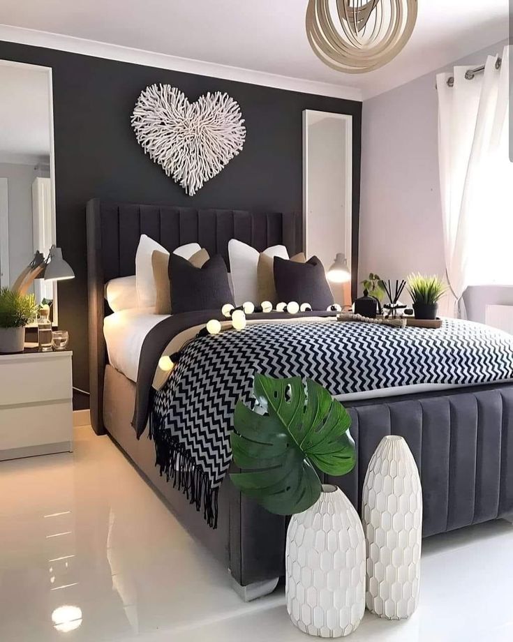 a bedroom with black and white decor on the walls, bed in the middle, two vases at the foot of the bed