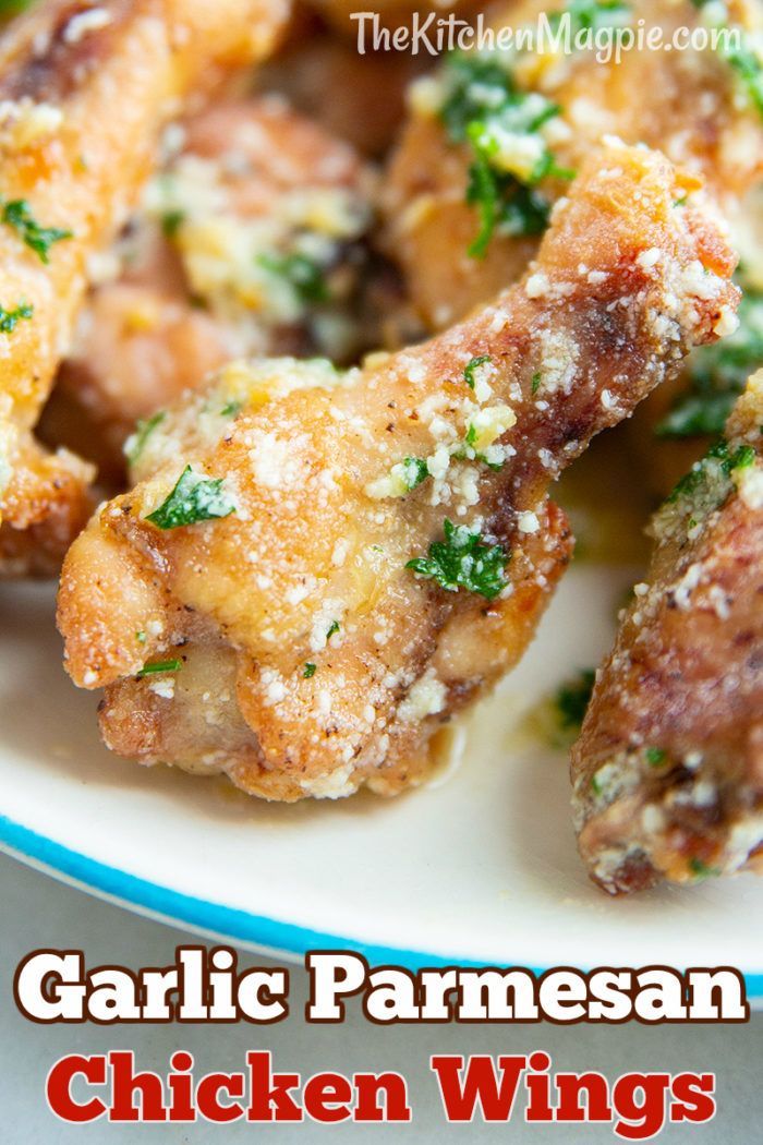 chicken wings covered in parmesan cheese and herbs on a white plate with blue trim