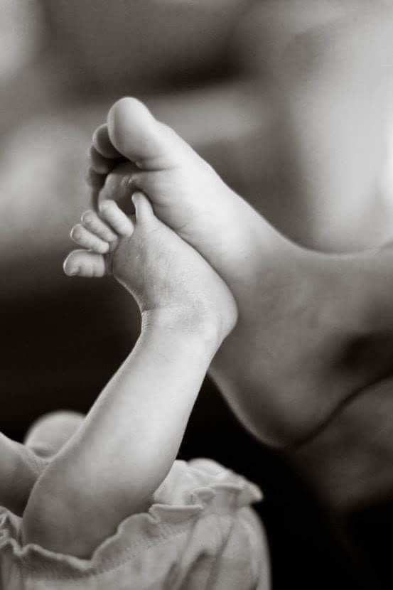 a black and white photo of a baby's foot being held in the air