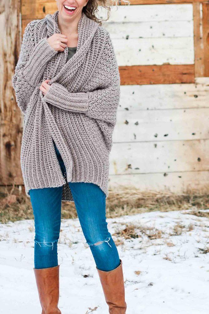 a woman standing in the snow wearing boots and a sweater