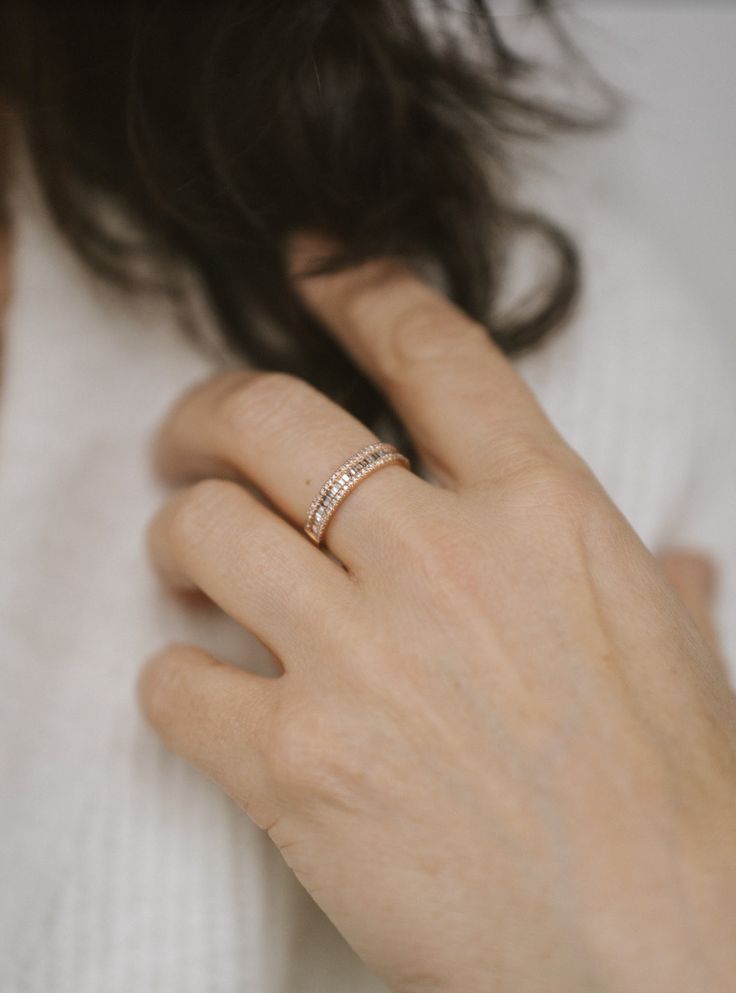 a woman's hand with a diamond ring on her left wrist, wearing a white sweater