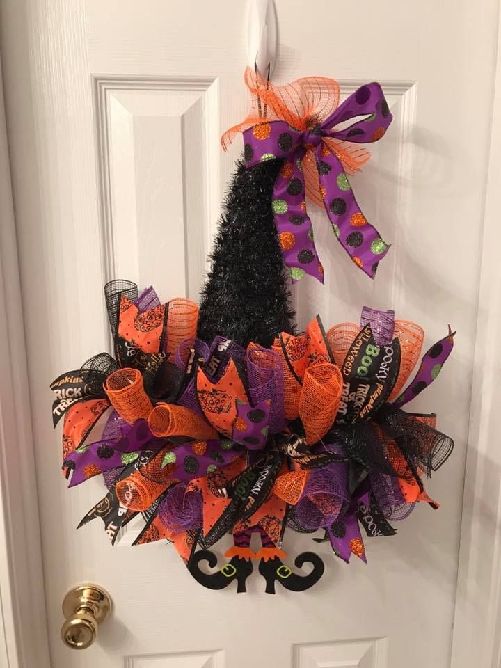 a door decorated for halloween with a witch's hat and pumpkins on it