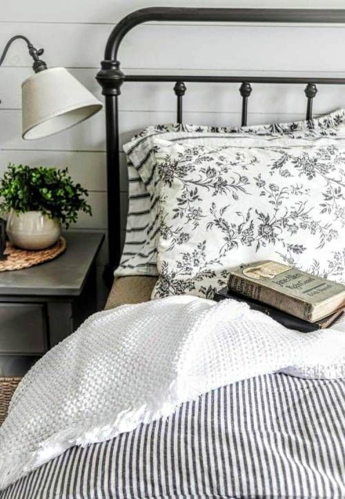 a black and white bed with striped sheets, pillows and a book on the end table