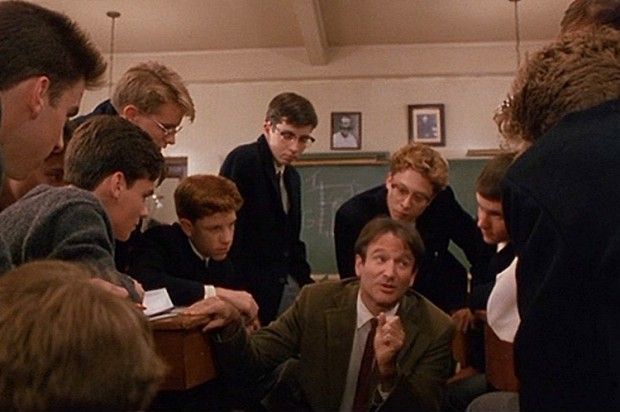 a group of young men standing around each other in a room with pictures on the wall