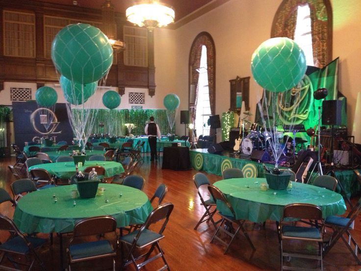 tables and chairs are set up in the middle of a room with green tablecloths